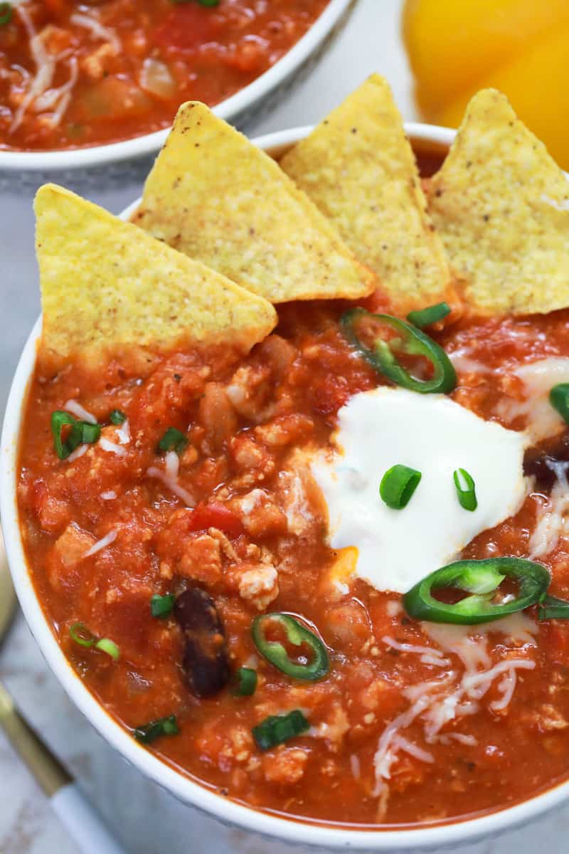 topping the chili with tortilla chips sour cream and jalapenos