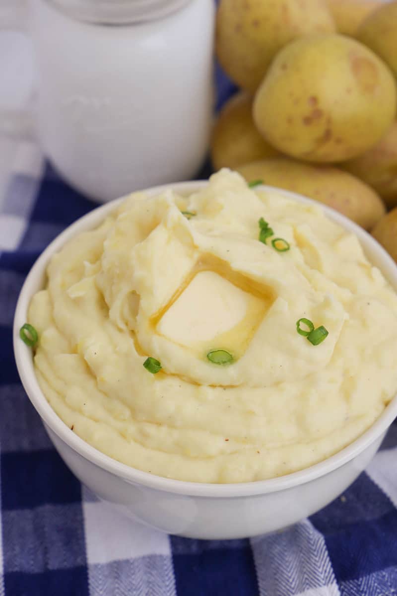 cream cheese mashed potatoes in white bowl topped with butter