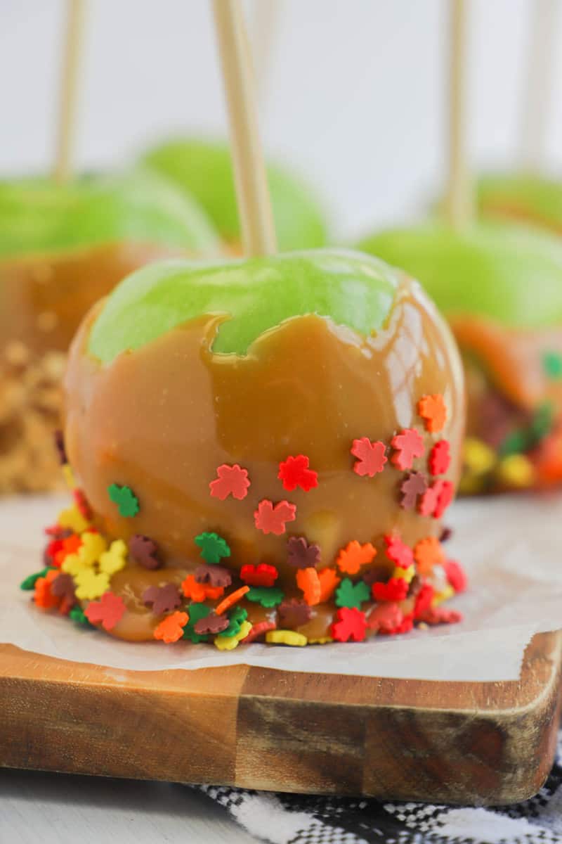 closeup picture of caramel apple with fall leave sprinkles