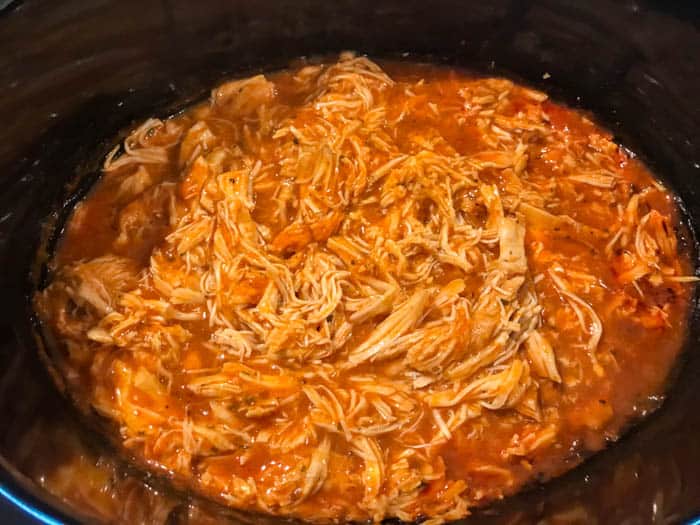 cooked and shredded buffalo chicken in slow cooker