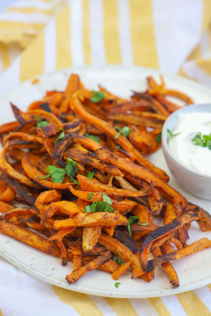 sweet potato fries on white plate with sour cream dipping sauce