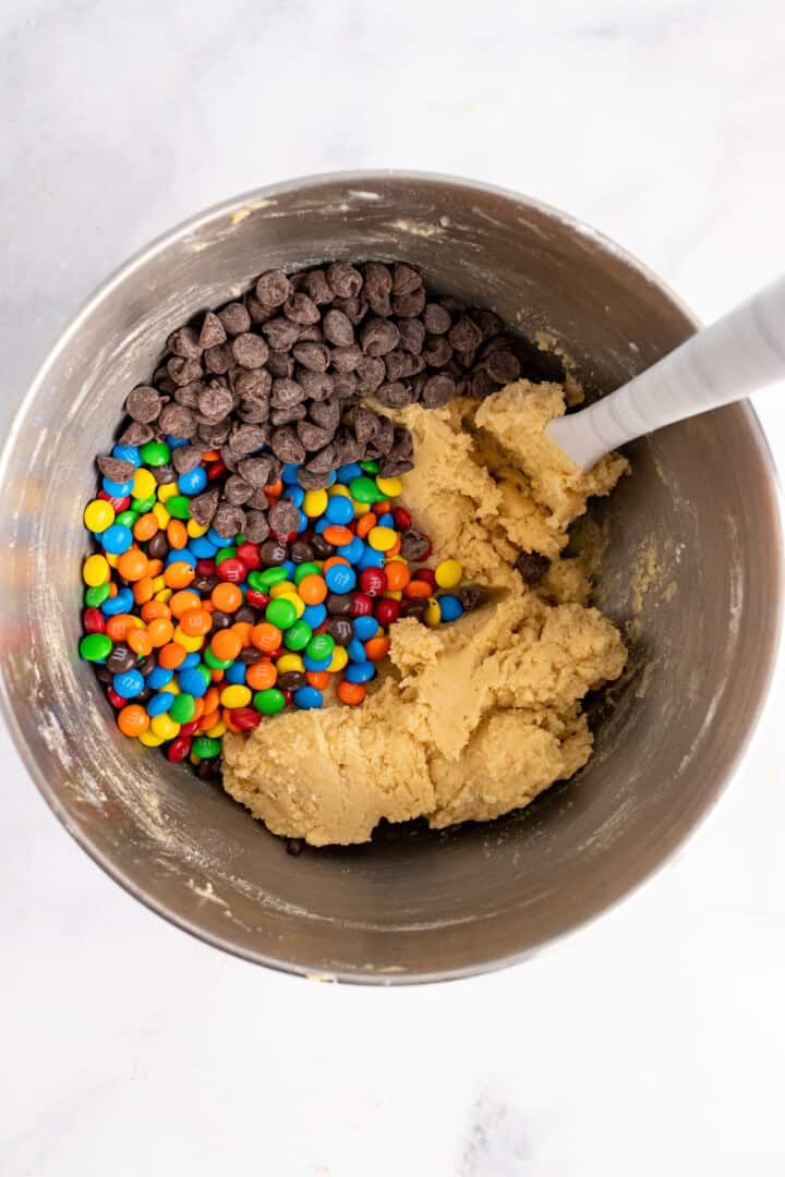 adding the m&ms and chocolate chips to the cookie dough