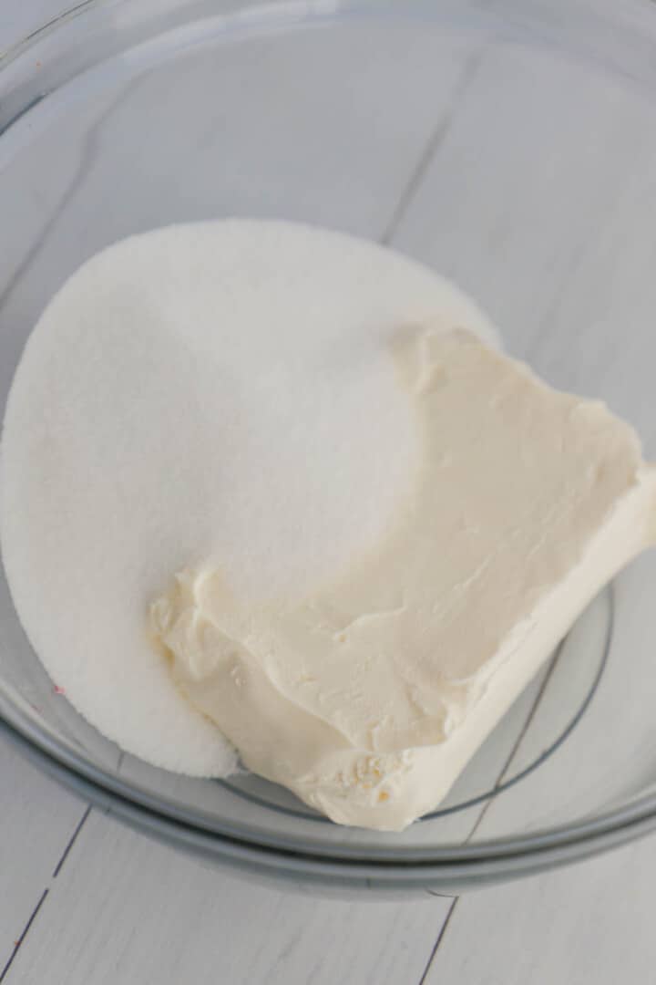 mixing together cream cheese and sugar in clear bowl