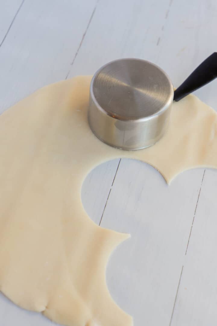 rolling out pie dough and cutting mini pie crusts