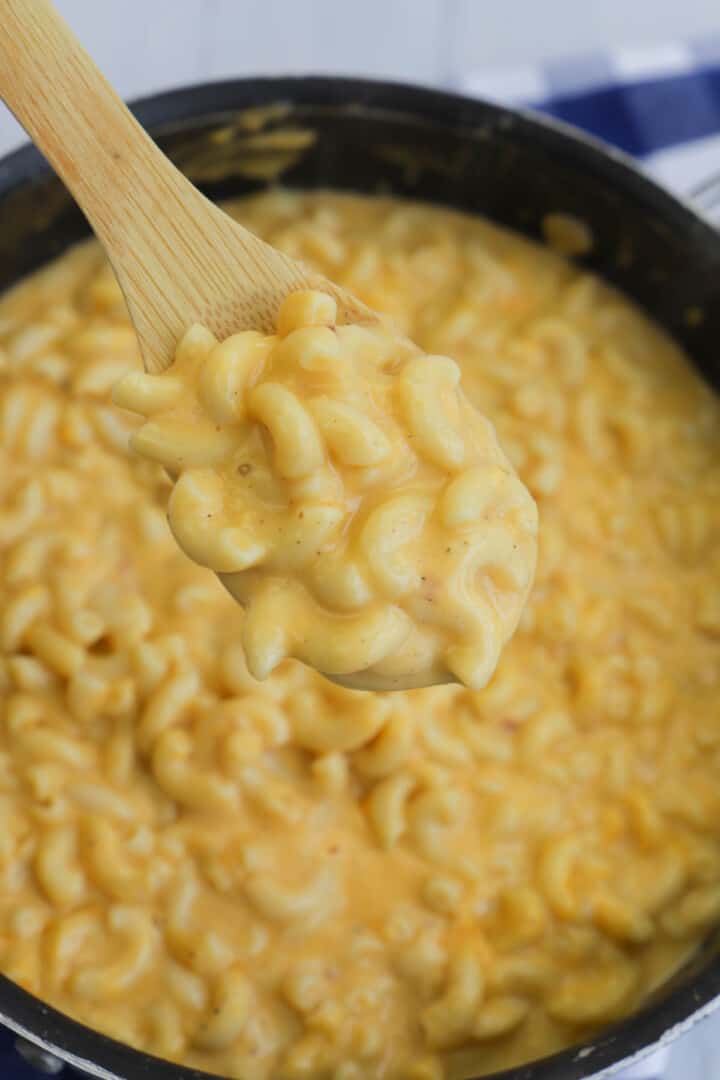 stove top mac and cheese being scooped out on wooden spoon