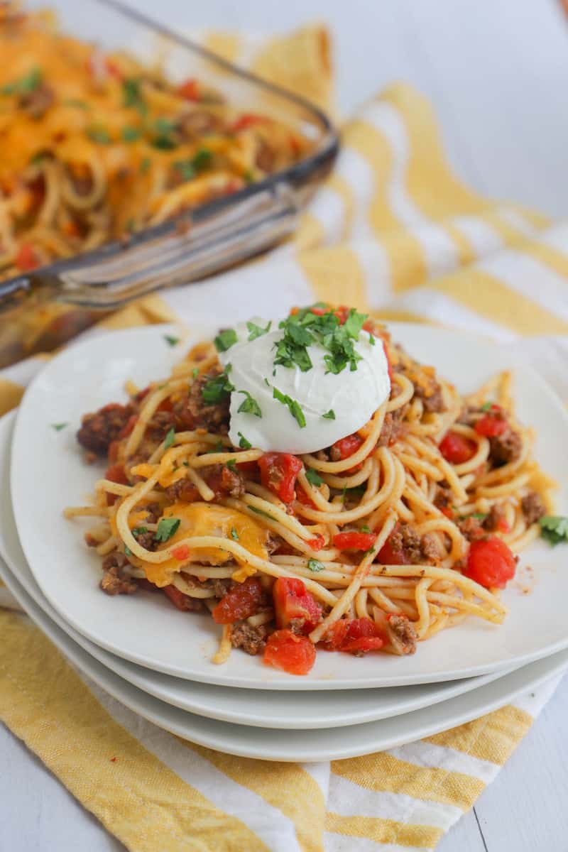 Taco Spaghetti on stacked white plates with sour cream on top