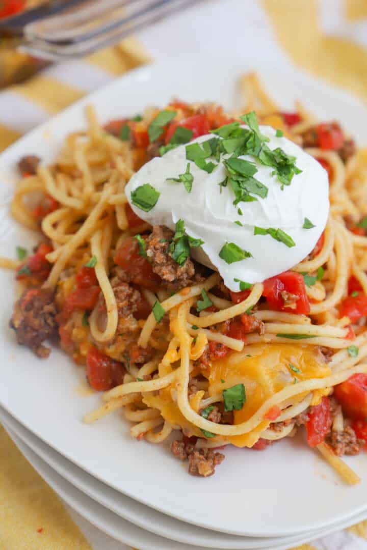 taco spaghetti on white plate topped with sour cream