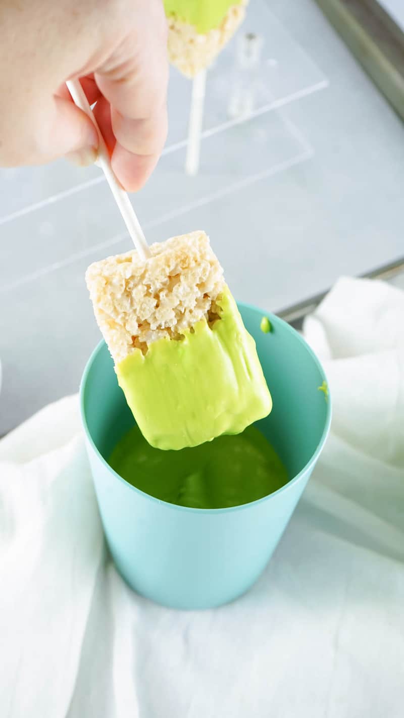 dipping rice krispie treat into candy coating