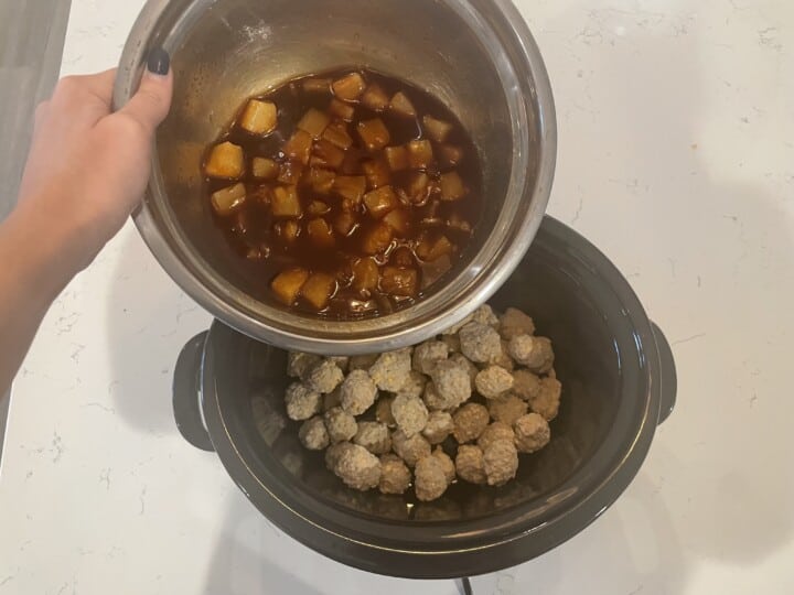 pouring BBQ pineapple mixture over meatballs in slow cooker