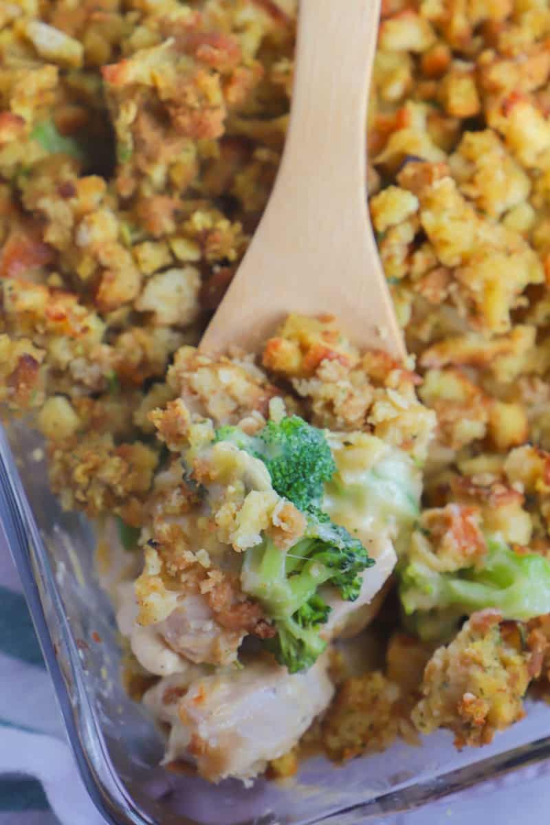 chicken stuffing casserole being scooped out of the casserole dish on a wooden spoon
