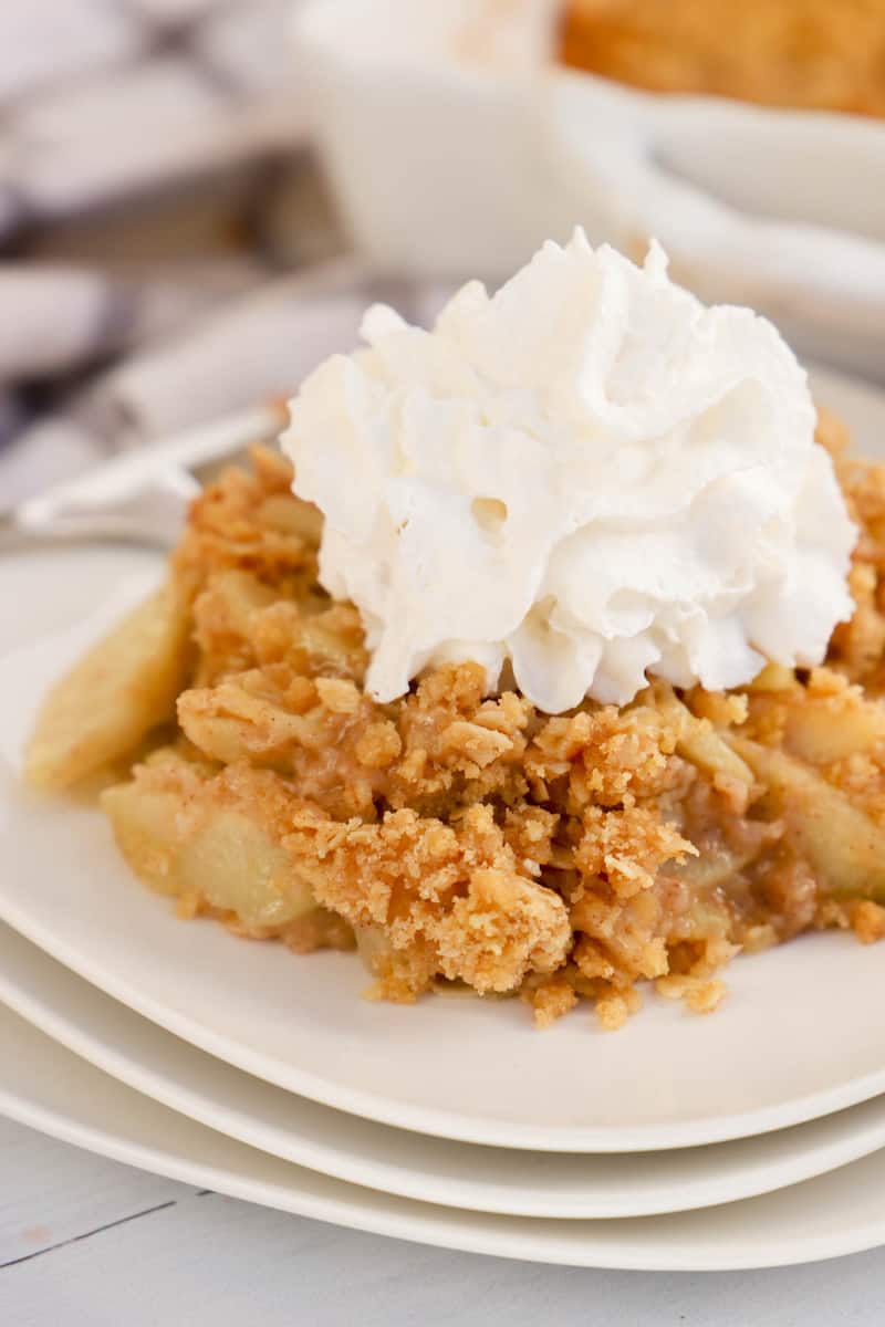 apple crisp on stacked white plates with whipped cream