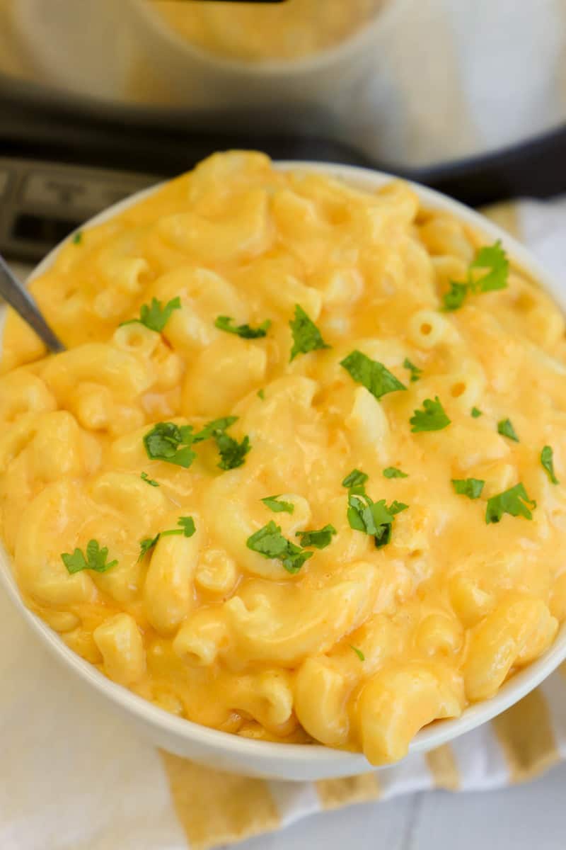 top down view of slow cooker mac and cheese in white bowl topped with parsley