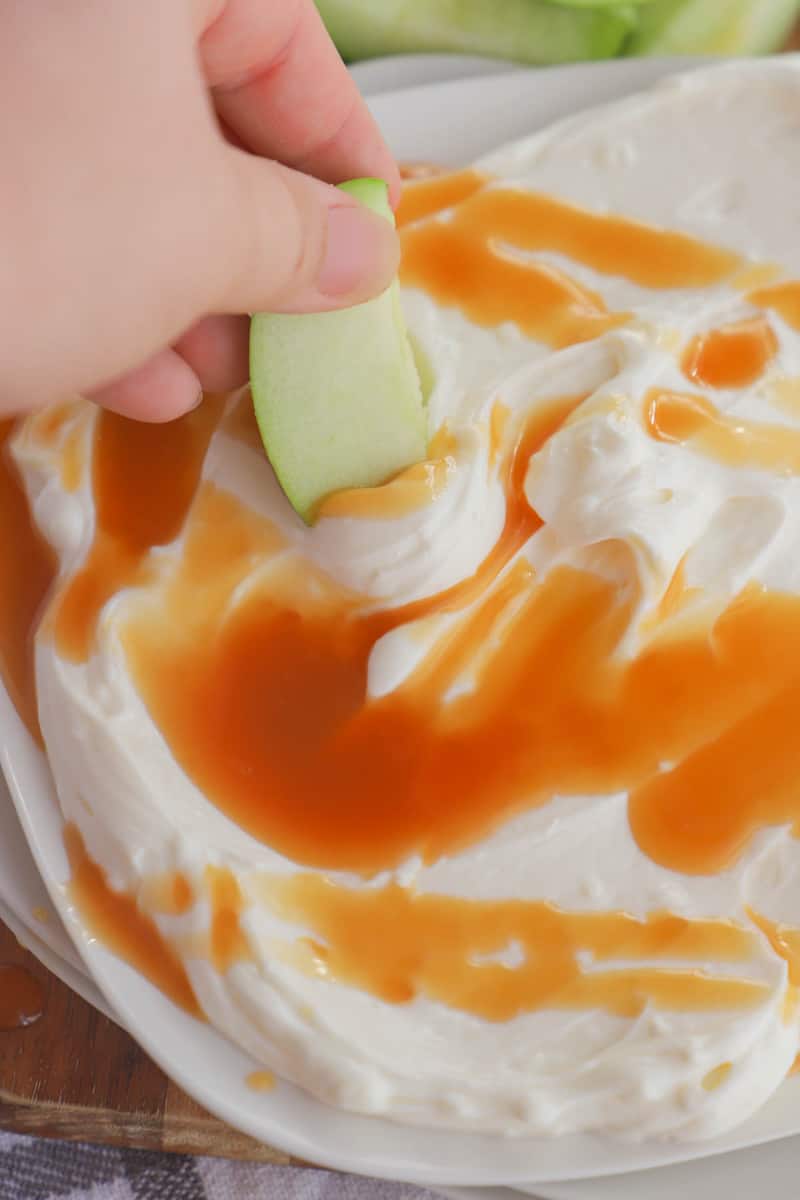 dipping an apple in the caramel cheesecake dip