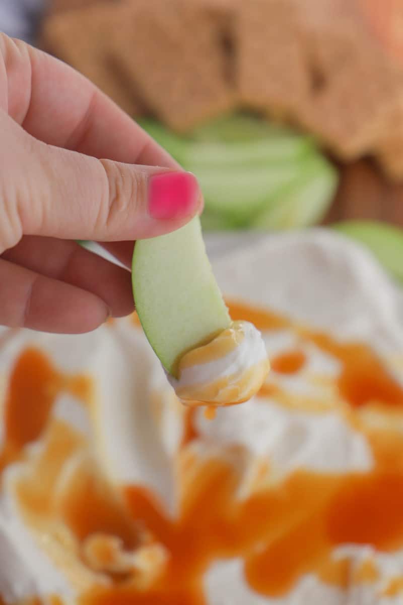 closeup of apple dipped in caramel cheesecake dip