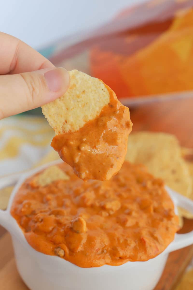 dipping a tortilla chip into the cheesy salsa dip