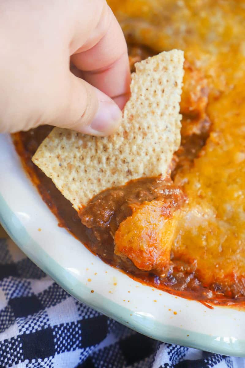 dipping a tortilla chip into the chili dip