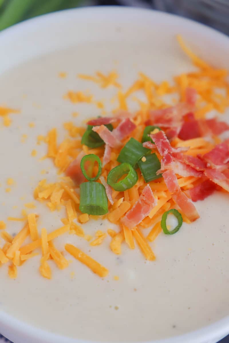 crock pot potato soup topped with bacon shredded cheese and green onions