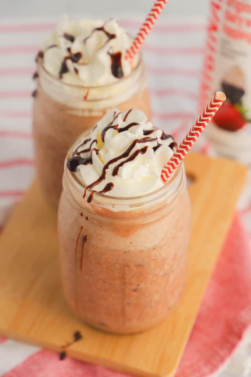 two frozen hot chocolates in mason jars on wooden board