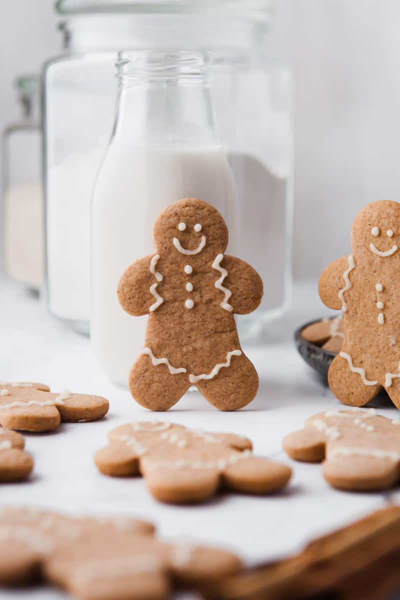 decorated gingerbread man standing up in front of a glass of milk