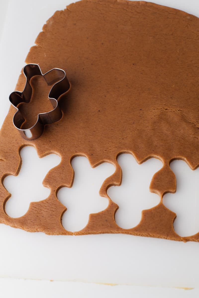 cutting the gingerbread men out with cookie cutter.