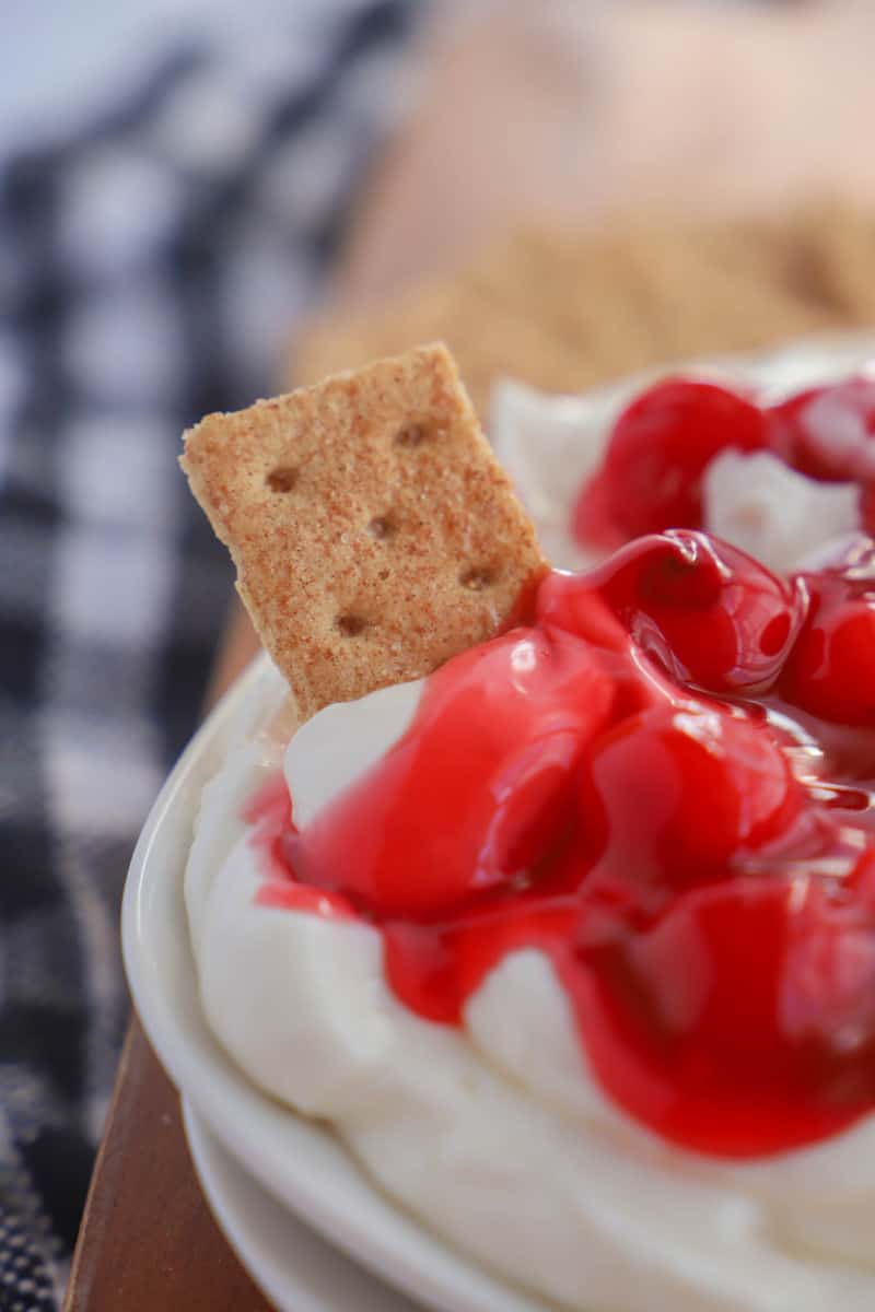 dipping graham cracker into cherry cheesecake dip