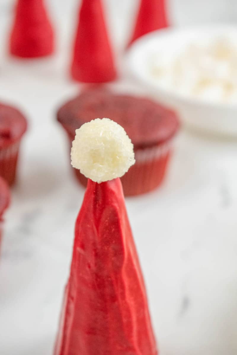 topping the cone hat with a marshmallow pom pom