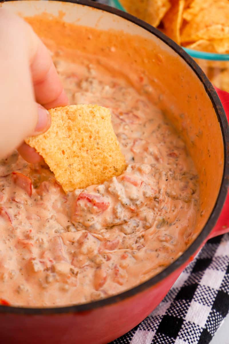 dipping a tortilla chip in to the sausage cream cheese dip