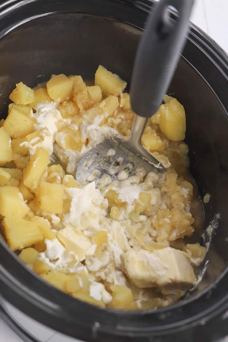 mashing the potatoes inside the slow cooker