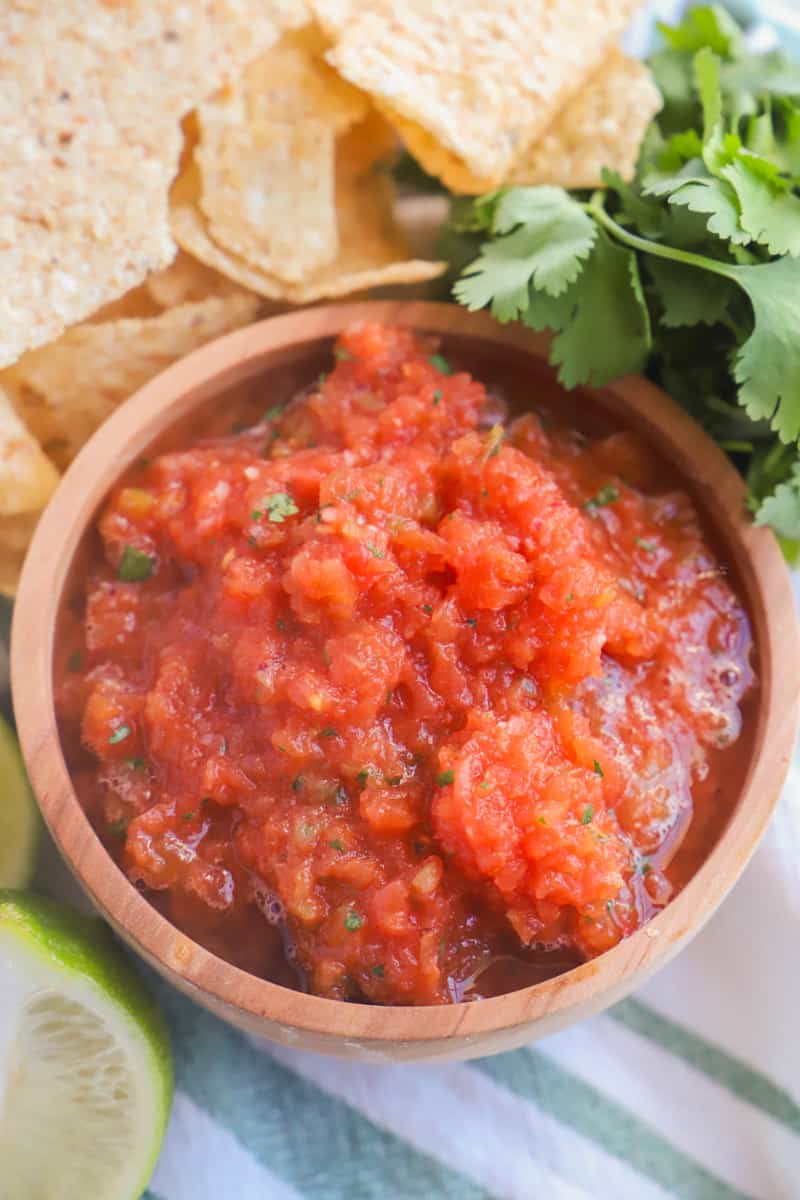homemade salsa in wooden serving bowl with tortilla chips and cilantro