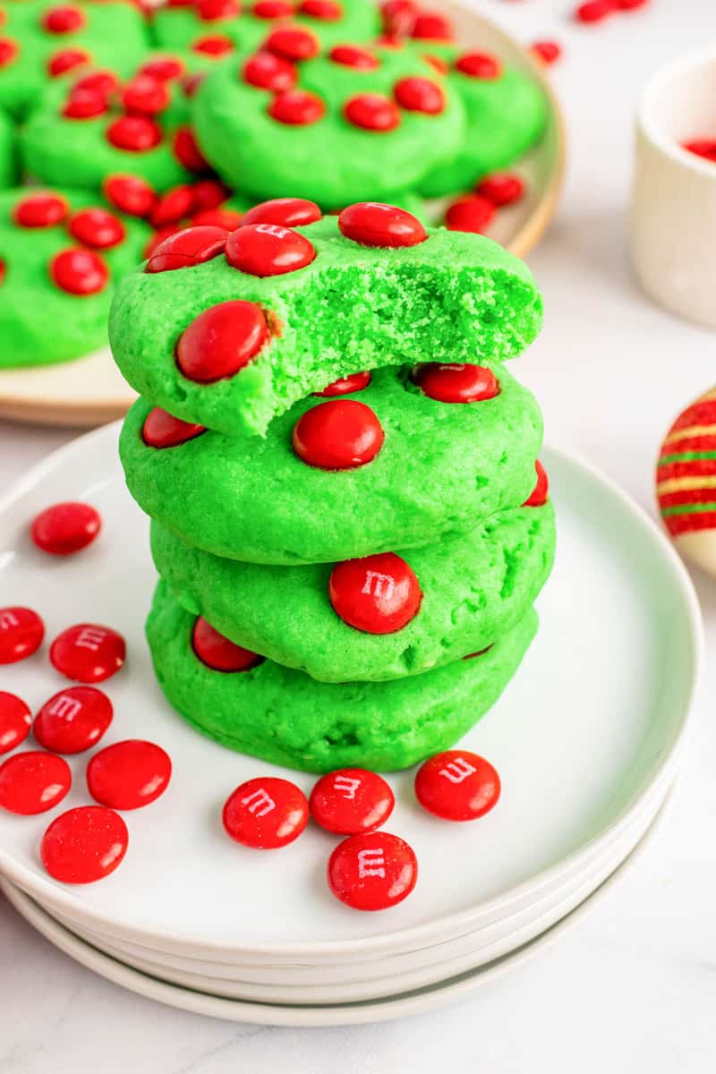 Grinch cookies stacked on white plates