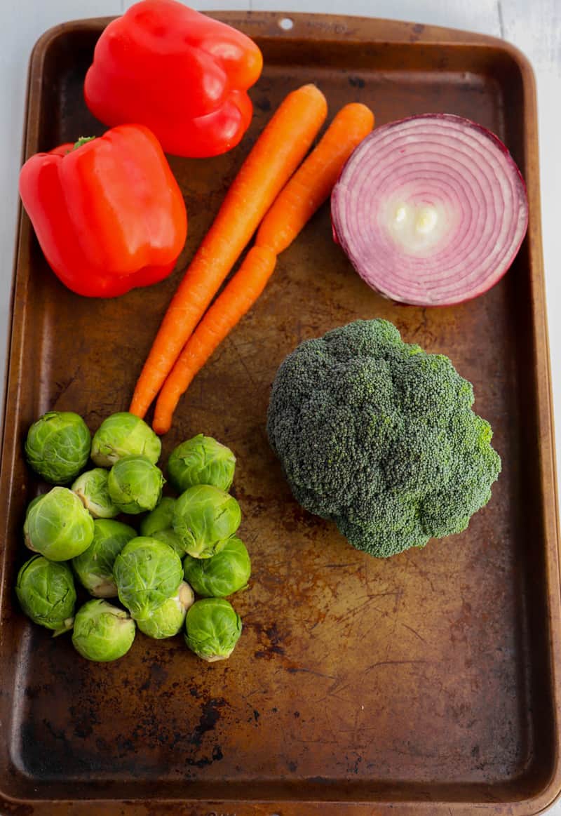 uncut peppers carrots Brussel Sprouts broccoli and onion on a baking sheet