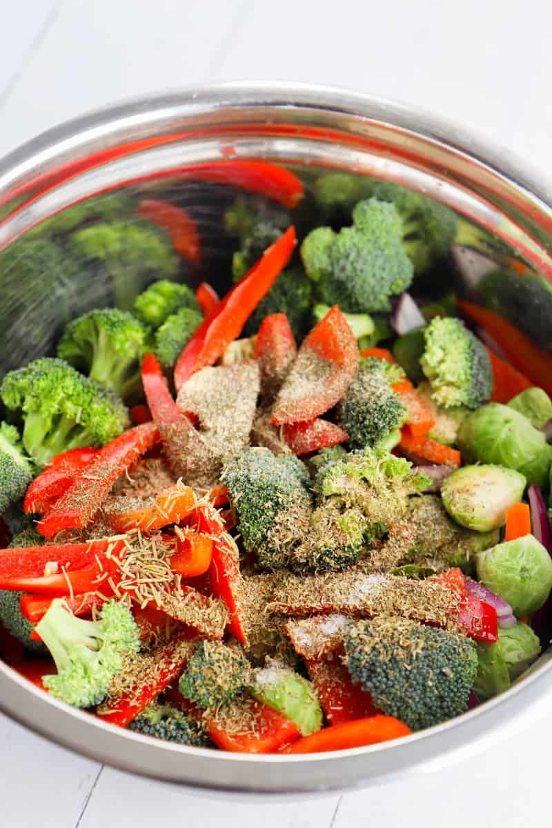 seasoning the vegetables in a metal bowl