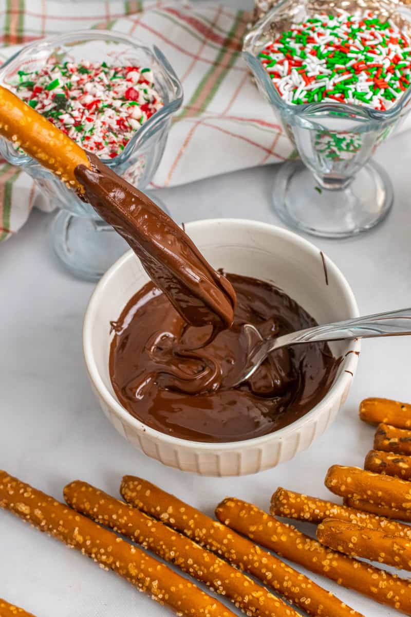 dipping and spreading the melted chocolate on to the pretzel rod.