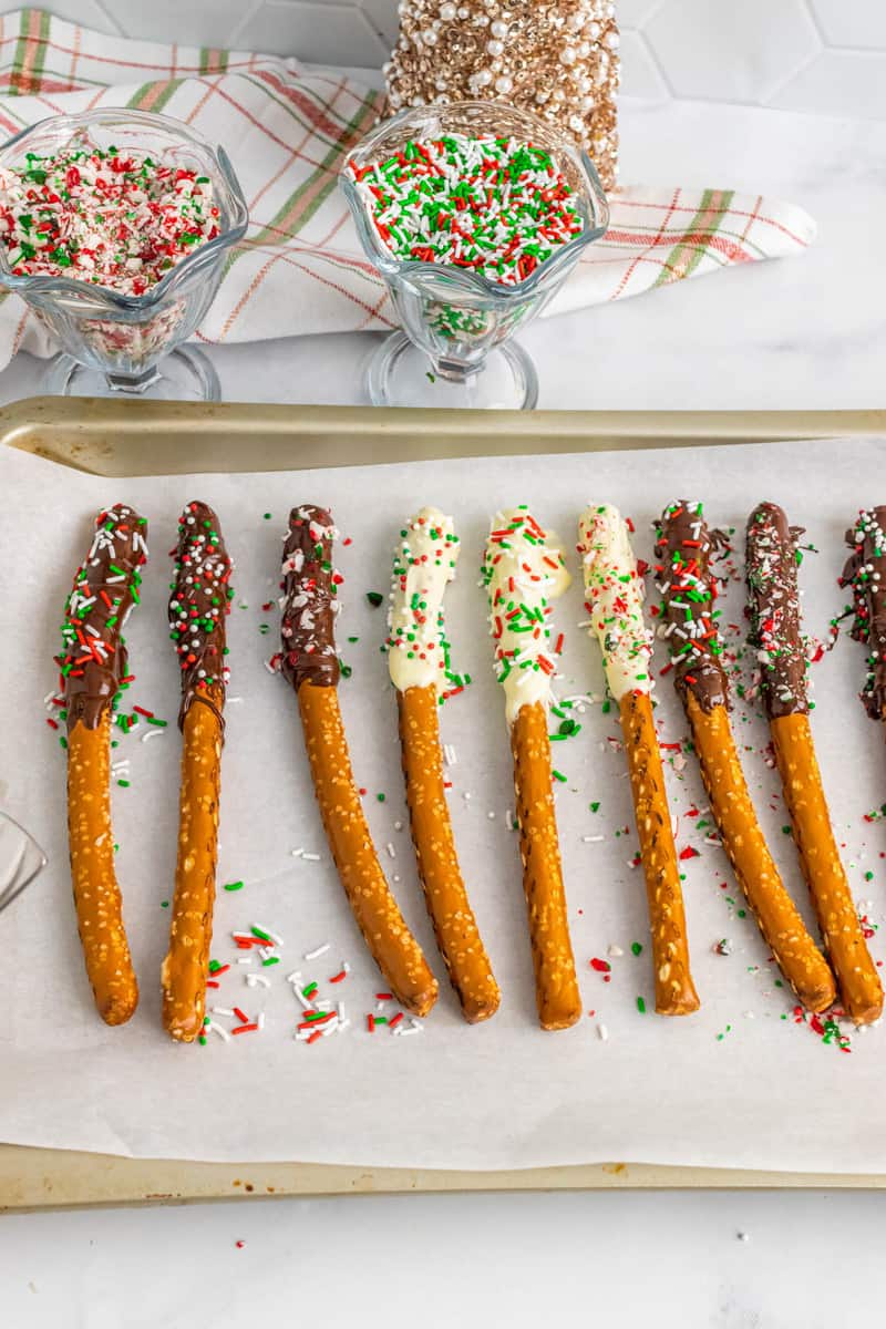 covered pretzel rods on a baking sheet with parchment paper.