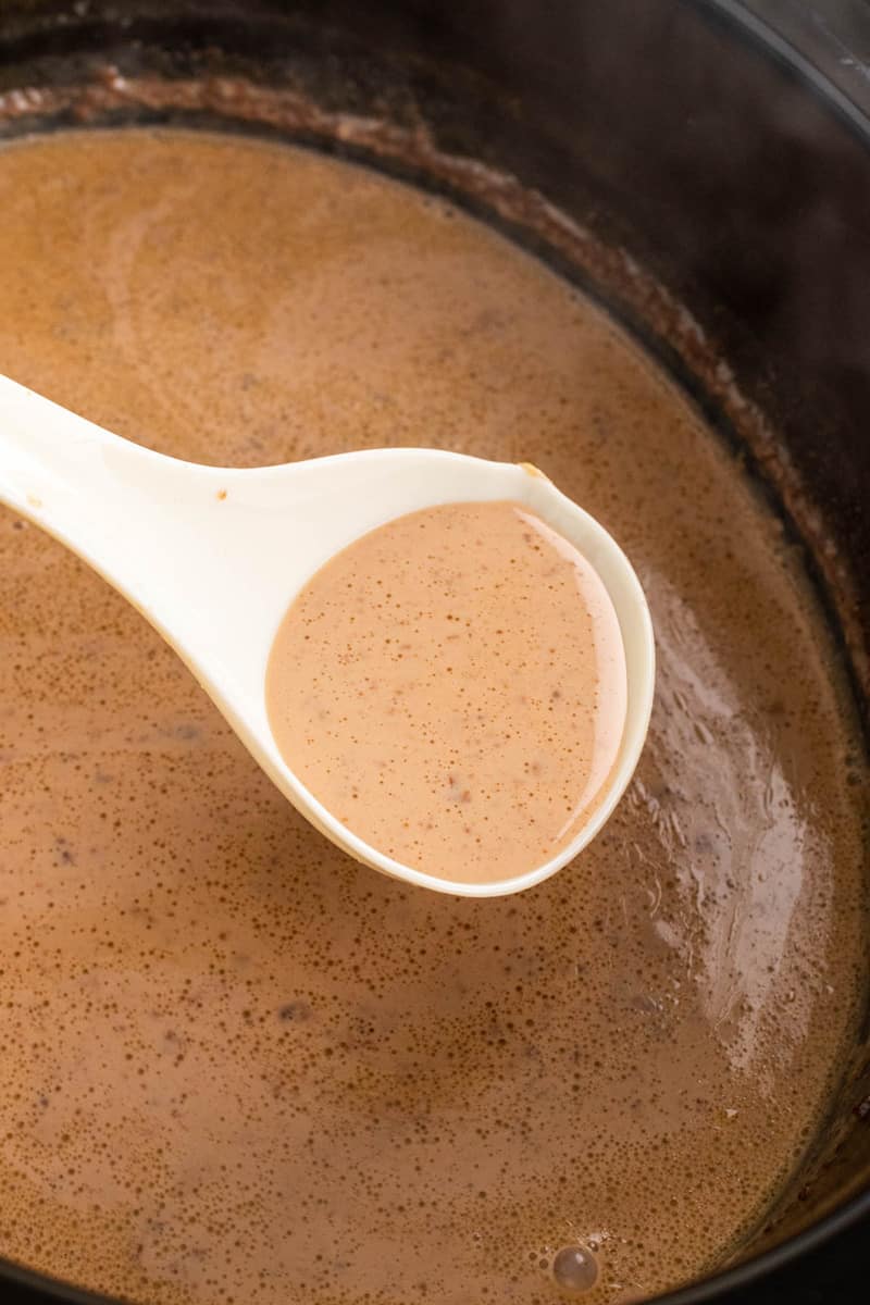 scooping hot chocolate out of the slow cooker