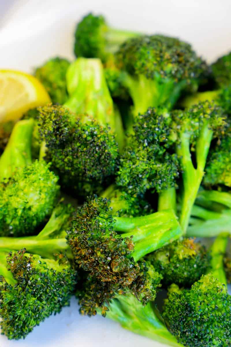 closeup of air fryer broccoli with lemon garnish
