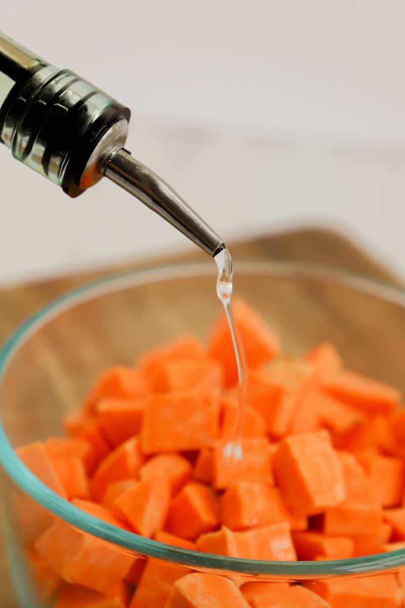pouring oil on the cubed sweet potatoes