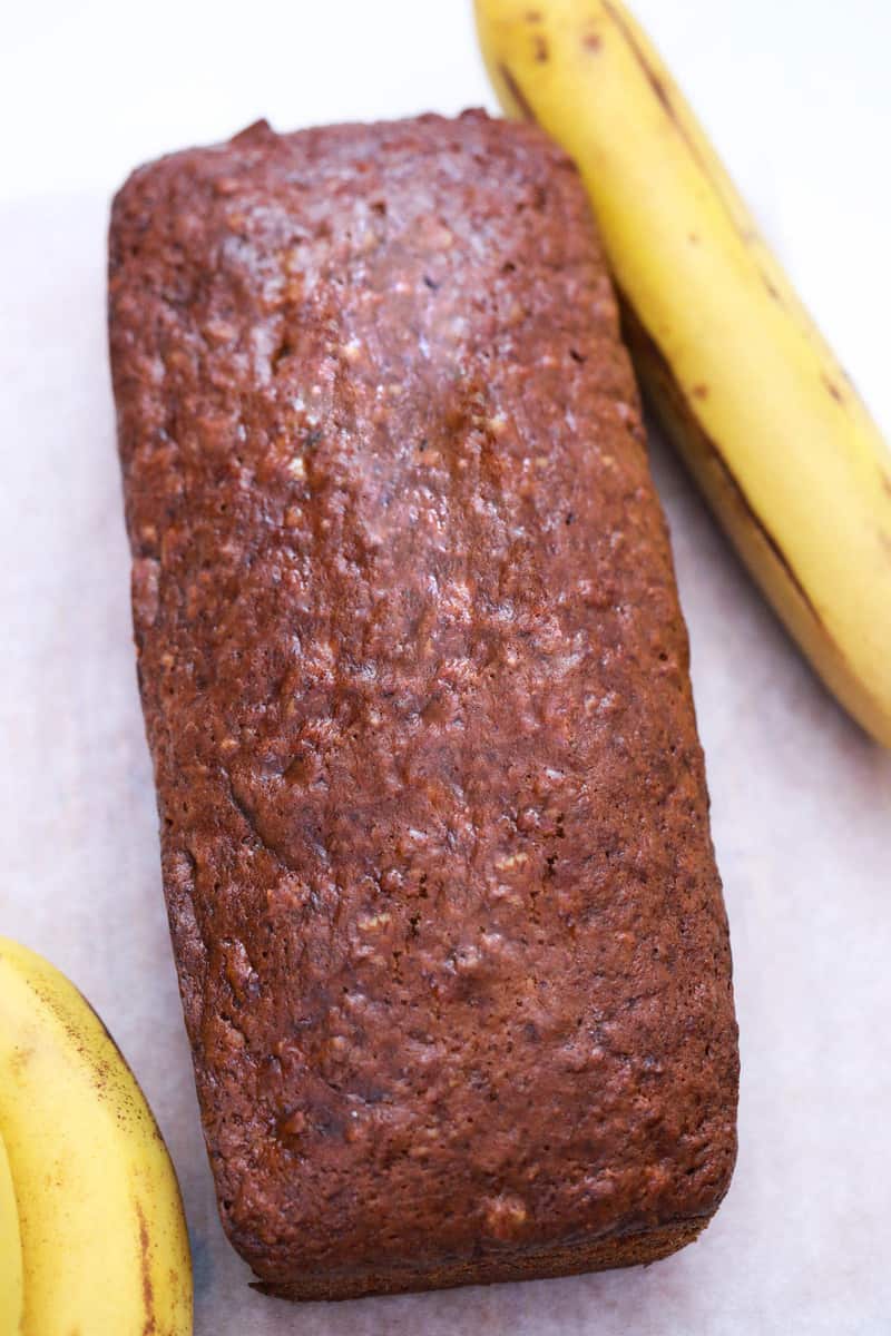 banana nut bread on countertop with bananas in background