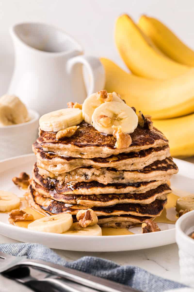 stack of the banana pancakes topped with walnuts and banana slices.