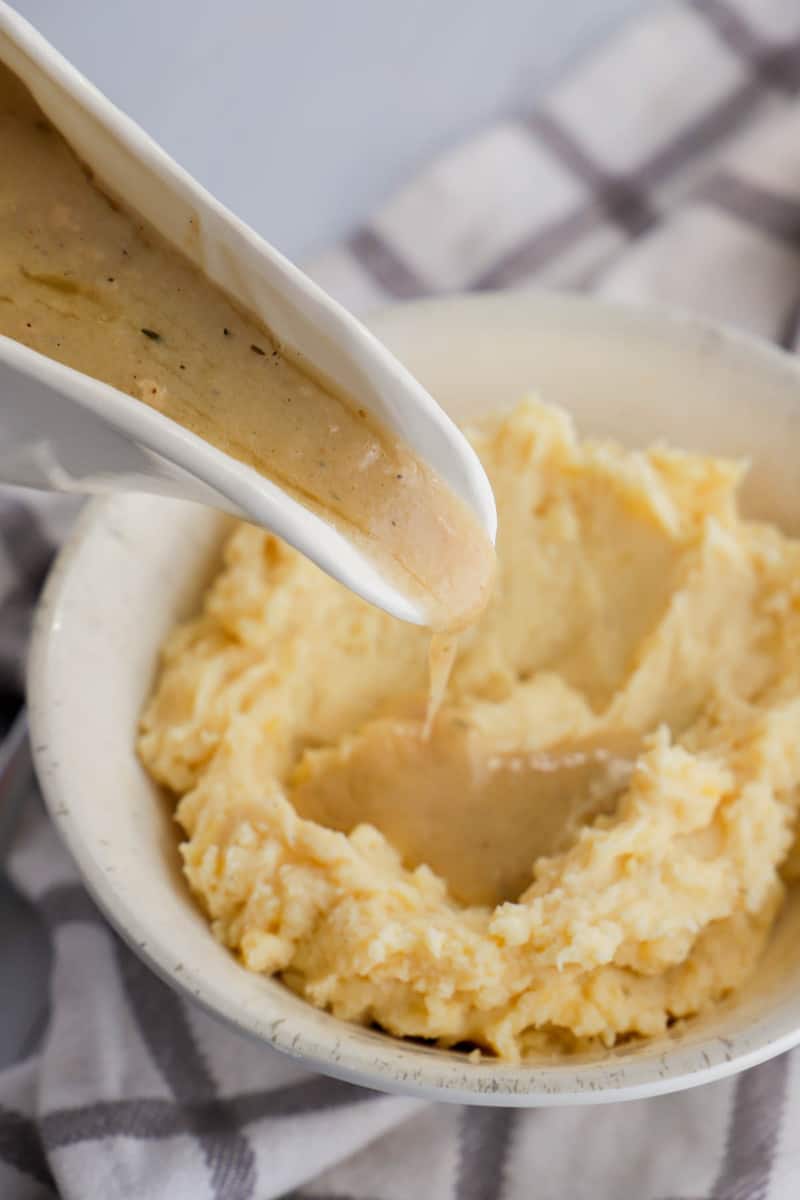 pouring gravy over mashed potatoes