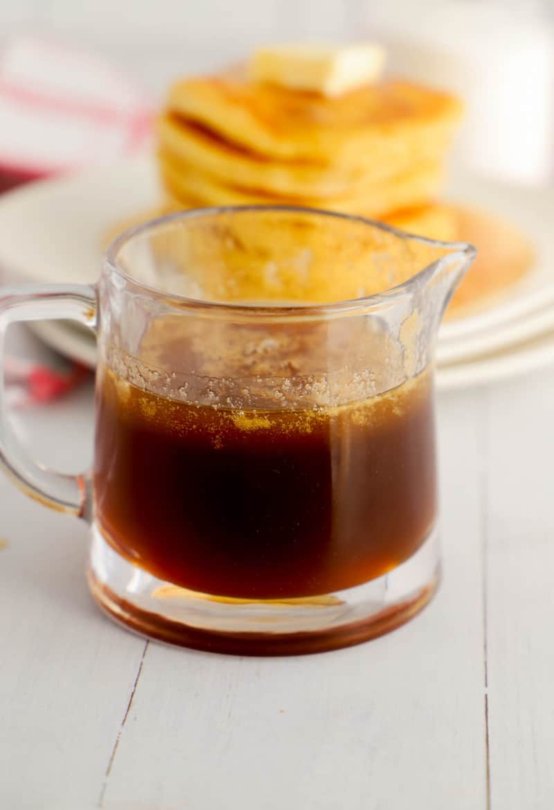 homemade pancake syrup in glass server with pancakes in the background