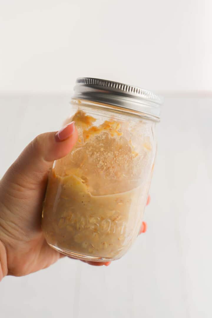 overnight oats in mason jar mixed in hand