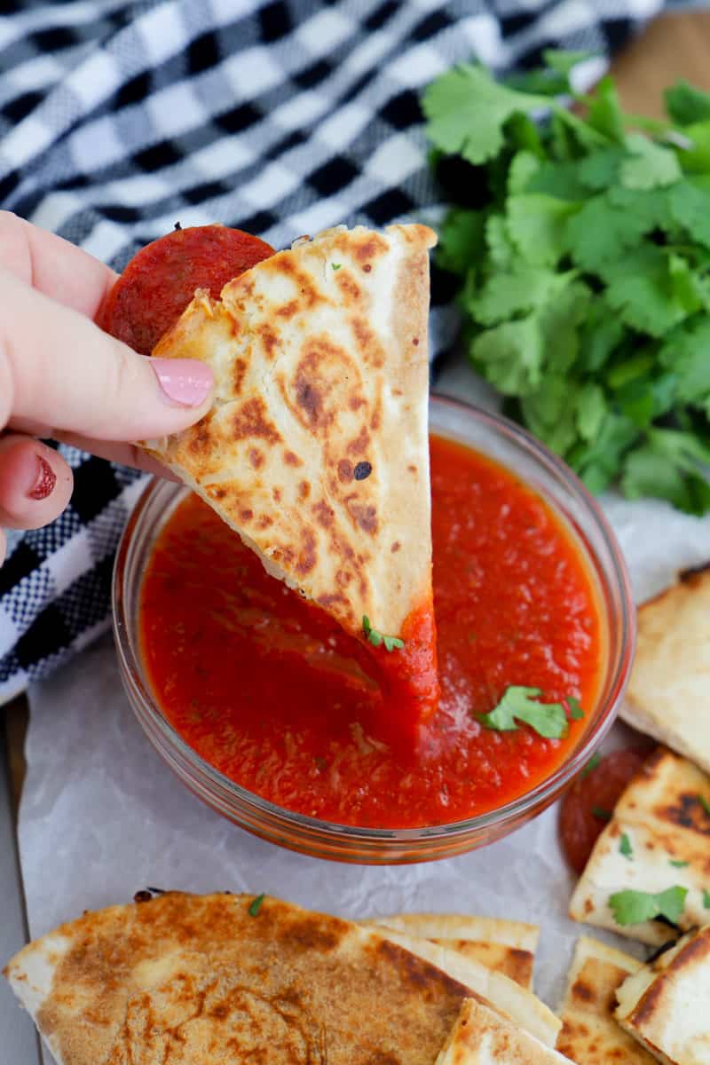 dipping the pizza quesadilla into the pizza sauce