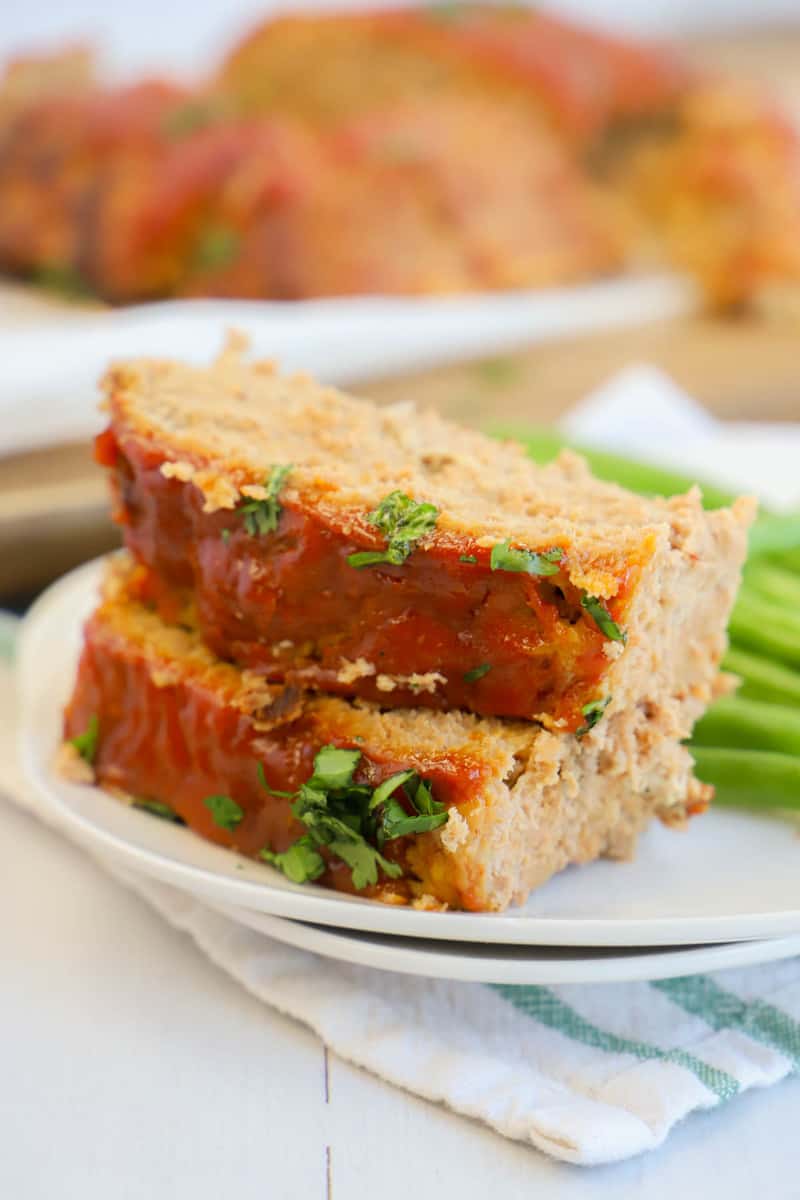 meatloaf slices on white plate with veggies on the side