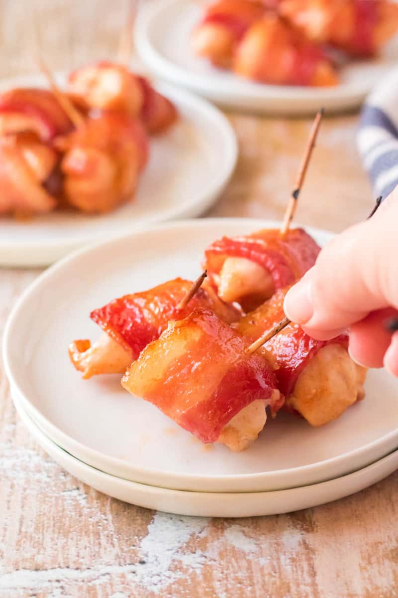 bacon wrapped chicken bites being grabbed with a toothpick on white plate