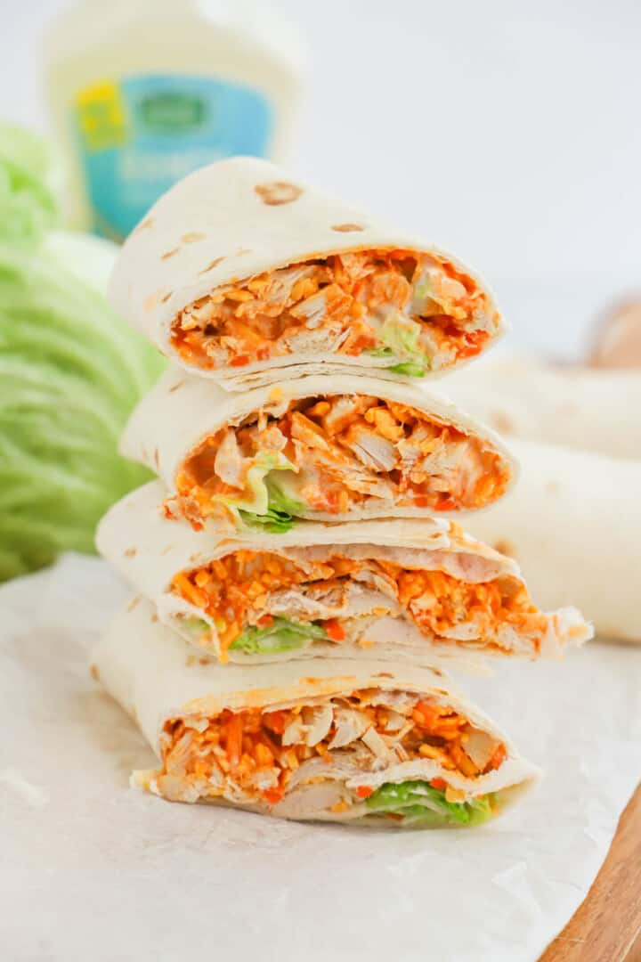 Buffalo Chicken Wraps stacked on parchment paper and wooden board