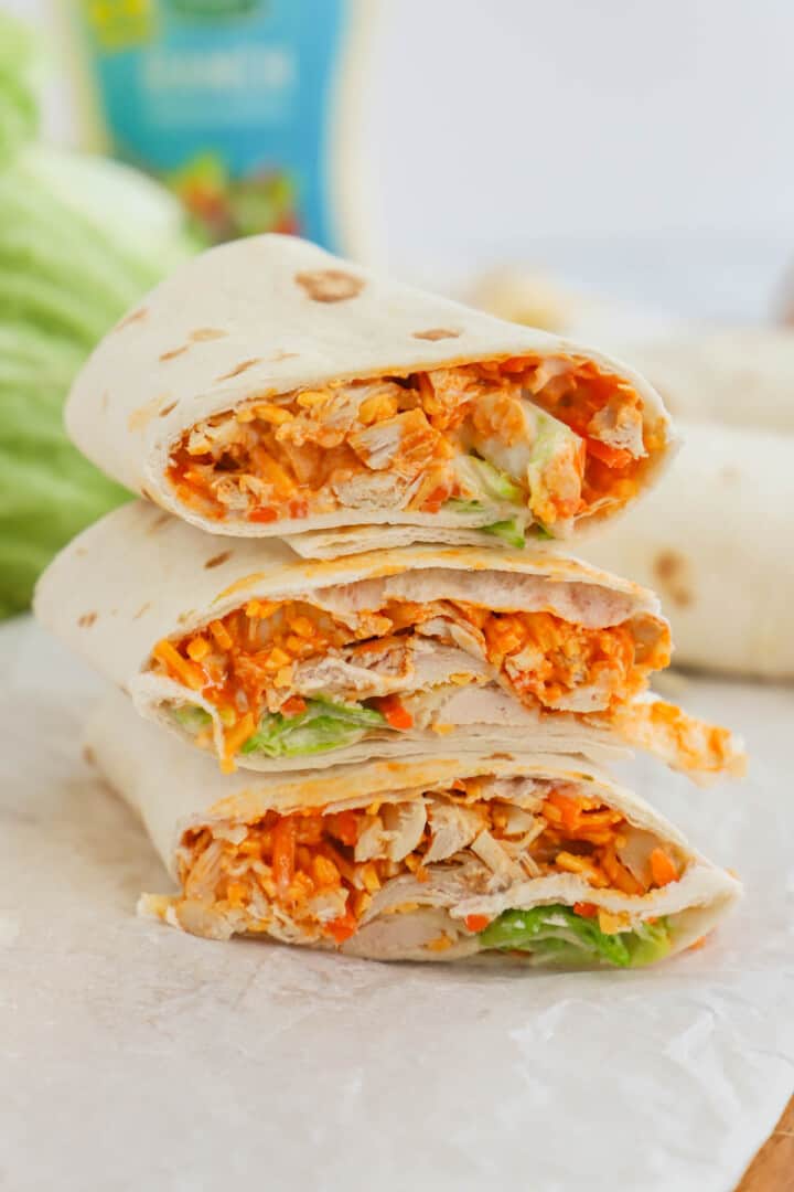 Buffalo chicken wraps stacked on parchment paper