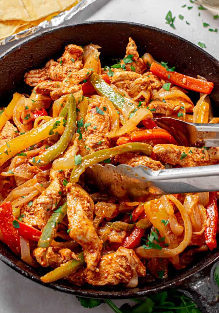 Chicken Fajitas in skillet with tongs