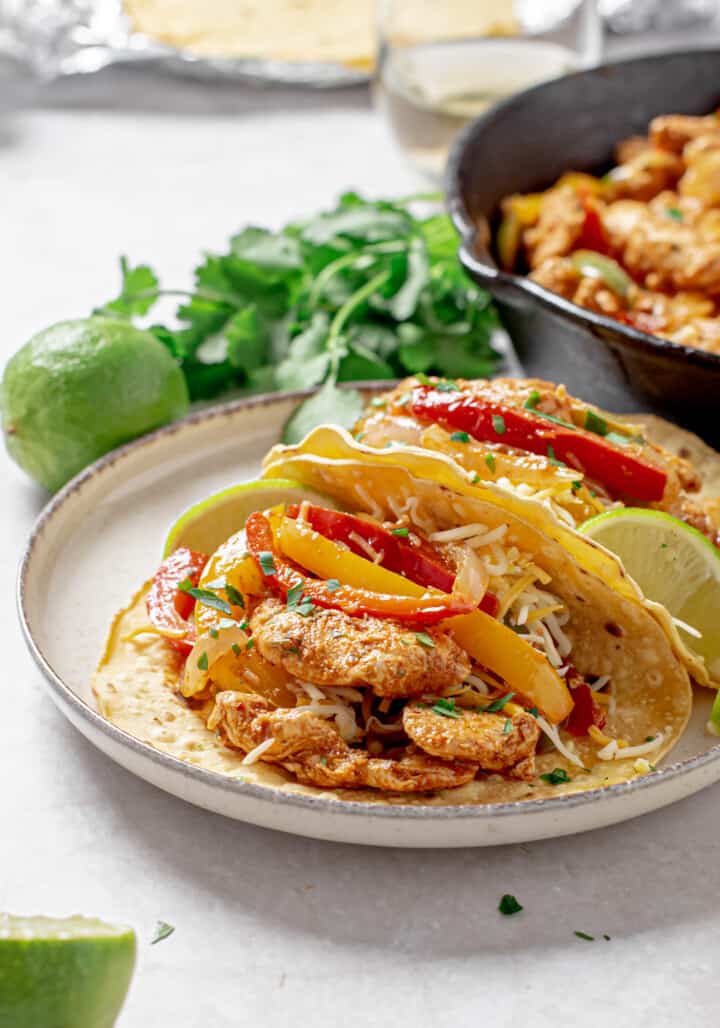 Chicken fajitas in corn tortillas with cheese and lime.