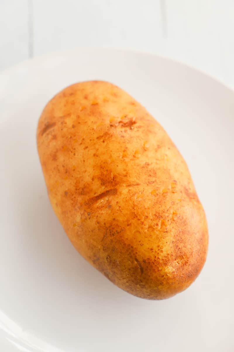 potato on white plate scrubbed for cooking